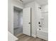 Neutral-toned bathroom with tub and shower combo and wood-look floors, with adjacent hallway at 261 Martin Spring Rd, Lawrenceville, GA 30045