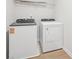 Well-lit laundry area with white washer and dryer and an overhead wire rack shelf at 711 Lily Blossom Path, Lawrenceville, GA 30045