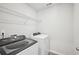 Well-equipped laundry room with modern washer and dryer, and overhead shelving for storage at 602 Wallace Oak Ln, Lawrenceville, GA 30045