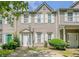 Tan two-story townhouse with green door, landscaping, and driveway at 142 Benfield Cir, Cartersville, GA 30121
