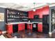 Modern basement bar with red cabinets, black appliances, and a white countertop at 9060 Selborne Ln, Chattahoochee Hills, GA 30268