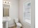 Half bath with pedestal sink, mirror, and window with blinds for natural light at 4235 Holland Grove Rd, Lawrenceville, GA 30044