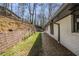 Backyard view showing retaining wall and side of home with landscaping and trees at 110 Maryeanna Ne Dr, Atlanta, GA 30342