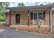 Close up of a brick home's covered front porch with chairs and a storm door at 72 Bishop Nw Dr, Cartersville, GA 30121
