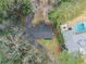 Aerial view of the house with a dark roof, surrounded by lush trees, a long driveway, and a refreshing pool at 4540 Club Valley Ne Dr, Atlanta, GA 30319