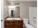 A bathroom featuring dual sinks, a bathtub, and brown cabinets at 1016 Weatherwood Pl, Conyers, GA 30012