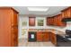 A kitchen featuring brown cabinets, a black dishwasher, and a window above the sink at 1016 Weatherwood Pl, Conyers, GA 30012