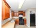 A kitchen featuring brown cabinets, a black refrigerator, and a black oven at 1016 Weatherwood Pl, Conyers, GA 30012