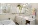 Bathroom featuring a vanity with marble countertop, soaking tub, and a large mirror reflecting the light from the window at 85 Sara Dr, Covington, GA 30016