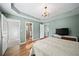 Spacious bedroom with neutral walls, hardwood floors, tray ceiling, television, and access to closet and bathroom at 85 Sara Dr, Covington, GA 30016