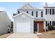 Two-story townhome with gray siding, brick accents, and a white garage door at 132 Timber Mist Ln, Lawrenceville, GA 30045