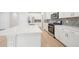 This kitchen features white cabinets, stainless steel appliances, and a large island with quartz countertops and wood flooring at 701 Lily Blossom Path Path, Lawrenceville, GA 30045