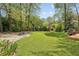 Large grassy backyard with mature trees and a gravel area, wooden deck on the right at 2947 Dunnington Cir, Chamblee, GA 30341