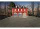 Front exterior of a red barn-style building featuring a wide driveway and three-car garage at 3970 Bridgeman Cir, Cumming, GA 30041