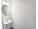 Small bathroom with pedestal sink and round mirror at 5823 Keystone Pt, Lithonia, GA 30058