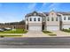 Two-story townhome with white and brick exterior, two-car garage, and landscaped lawn at 8194 Tiger Way, Riverdale, GA 30296
