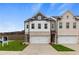 New construction townhome features a brick facade, two-car garage, green lawn, and concrete driveway at 8194 Tiger Way, Riverdale, GA 30296