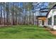 View of the backyard with a manicured lawn, mature trees, and the back of the house with patio at 1820 Lake Dow Rd, Mcdonough, GA 30252