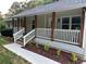 Eye-level view of a relaxing porch featuring stained wood columns, white railings, and manicured landscaping at 641 Virginia Ave, Suwanee, GA 30024