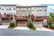 Townhome's rear exterior featuring elevated decks over drive-under garages; three units depicted with varied facade colors at 4196 Morrison Way # 11, Atlanta, GA 30341