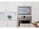 Close up on the stainless steel microwave and oven with white cabinets and herringbone tile backsplash at 812 Stratford Rd, Avondale Estates, GA 30002