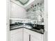 Elegant wet bar with granite countertop, glass shelving, mirrored backsplash, and white cabinetry at 3456 Paces Nw Pl, Atlanta, GA 30327