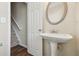 Bright powder room featuring a pedestal sink, decorative mirror, and wood flooring at 2159 Meadow Peak Rd, Duluth, GA 30097