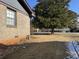 Side yard view of house with mature tree and patchy grass at 457 Castleaire Dr, Stone Mountain, GA 30087