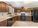 Galley kitchen with wood cabinets, tile flooring and black appliances at 730 Lake Forest Pass, Roswell, GA 30076