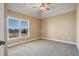 This bedroom features neutral walls, plush carpeting, a tray ceiling with fan, and a bright window at 2602 Alcovy Club Dr, Dacula, GA 30019