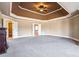 Spacious carpeted primary bedroom with decorative tray ceiling and doorway into the ensuite at 2602 Alcovy Club Dr, Dacula, GA 30019