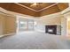 Primary bedroom with a fireplace, tray ceiling, large windows, and neutral carpet at 2602 Alcovy Club Dr, Dacula, GA 30019