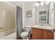 Bathroom with a bathtub/shower combo, wood vanity, sink, commode, and a decorative mirror at 3901 Old Atlanta Station Se Dr, Atlanta, GA 30339