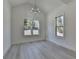 Bright living area with large windows, light wood floors, vaulted ceiling, and modern chandelier at 7650 Abbey Glen Dr, Cumming, GA 30028