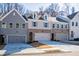 Three-unit townhome building with gray and brick exterior, two-car garages, and landscaping at 143 Bluffington Way, Marietta, GA 30066