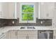 Close-up of bright kitchen with stainless appliances, gray backsplash, and plenty of countertop space at 116 Cottage Gate Ln, Roswell, GA 30076