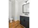Stylish powder room with modern fixtures, wood floors, and a framed mirror at 116 Cottage Gate Ln, Roswell, GA 30076