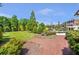Expansive backyard featuring lush lawn, mature trees, and a meandering brick path leading to the residence at 5200 Moore Rd, Suwanee, GA 30024