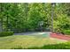 Private backyard basketball court surrounded by mature trees and manicured landscaping at 5200 Moore Rd, Suwanee, GA 30024