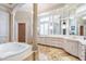 Elegant bathroom with soaking tub, marble floors, decorative columns and a vanity with mirrors at 5200 Moore Rd, Suwanee, GA 30024