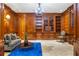 Wood-paneled library with built-in bookshelves, a cozy couch, and elegant chandelier at 5200 Moore Rd, Suwanee, GA 30024
