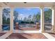 Covered outdoor living area with large columns overlooking an iron fence, mature trees and backyard structures at 5200 Moore Rd, Suwanee, GA 30024