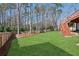 The grassy backyard is surrounded by a fence and trees, and features stairs up to the deck at 1449 Brentford Cv, Snellville, GA 30078