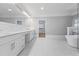 Bright bathroom with white marble floors, white cabinets, and a standalone tub at 4267 Matisse Ln, Fairburn, GA 30213