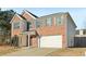 Brick two-story house with a white two-car garage and landscaping at 6897 Estepona St, Atlanta, GA 30349