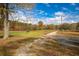 Scenic shot of a grassy yard along a gravel road with mature trees and fall colors at 105 Tranquillity Dr, Villa Rica, GA 30180