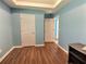 Light blue bedroom with wood-look floors, a closet, and access to other rooms at 1734 Spring Hill Cv, Lithonia, GA 30058