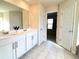 Bright bathroom with a double vanity, tile floor and a view into an organized closet at 799 Blue Juniper Cir, Loganville, GA 30052