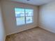 Bright bedroom with neutral walls and carpet, featuring a large window with blinds at 799 Blue Juniper Cir, Loganville, GA 30052