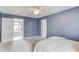 Bedroom featuring a bed, ceiling fan, and neutral carpet, set against blue walls at 1692 Branch Creek Cv, Lawrenceville, GA 30043